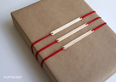 three brown wrapped gifts with red string on them