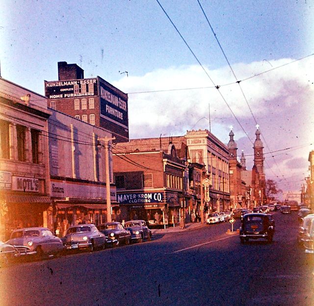 an old photo of cars driving down the street