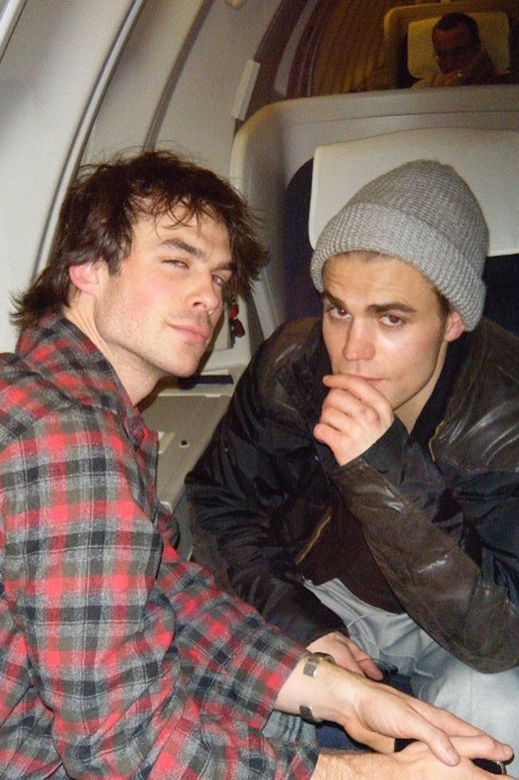 two young men sitting on an airplane looking at something in the distance with their hands under their chins