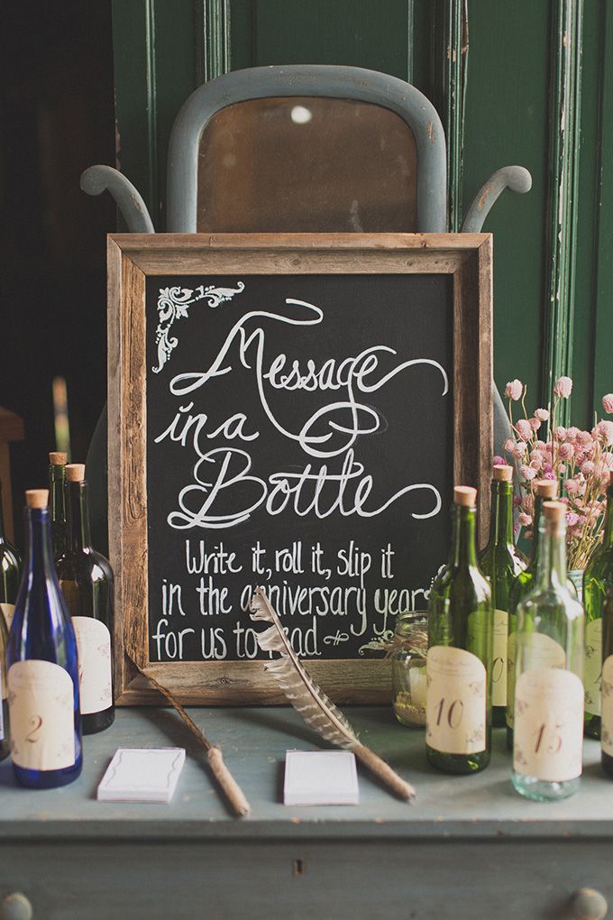 a chalkboard sign sitting on top of a table next to wine bottles and candles