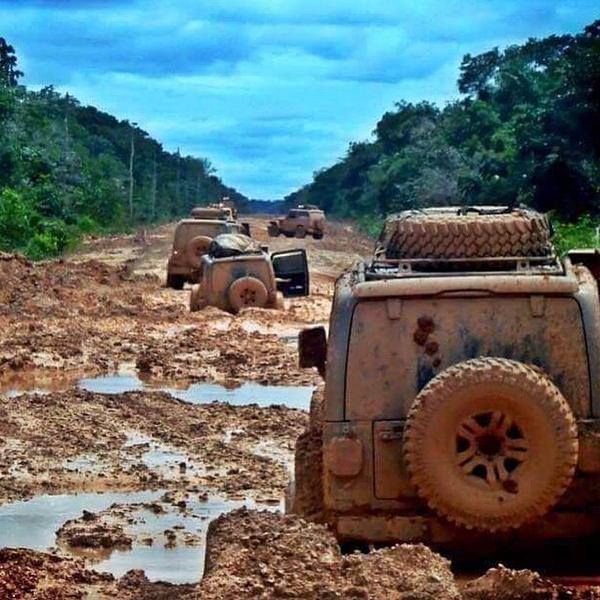 several jeeps are stuck in the mud on a dirt road