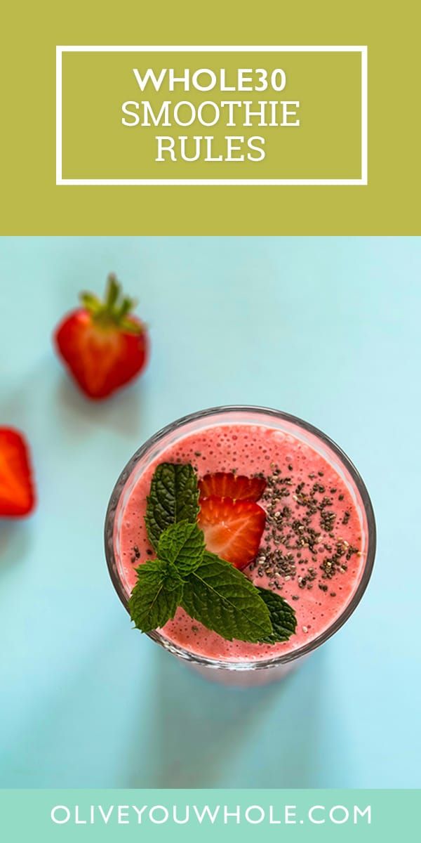 a smoothie with strawberries and mint in it on a blue table next to strawberries