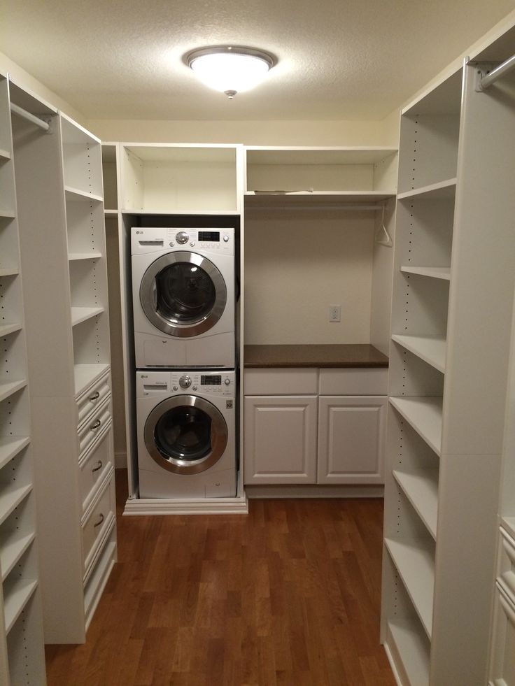 a washer and dryer are in the corner of this laundry room with white shelving