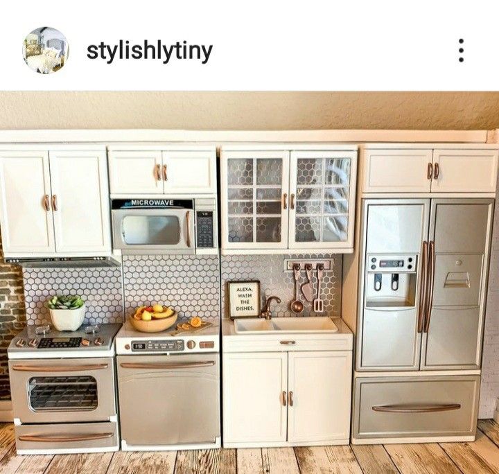 a model kitchen with white cabinets and silver appliances