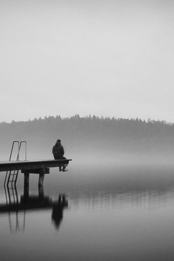 a person sitting on a dock in the fog