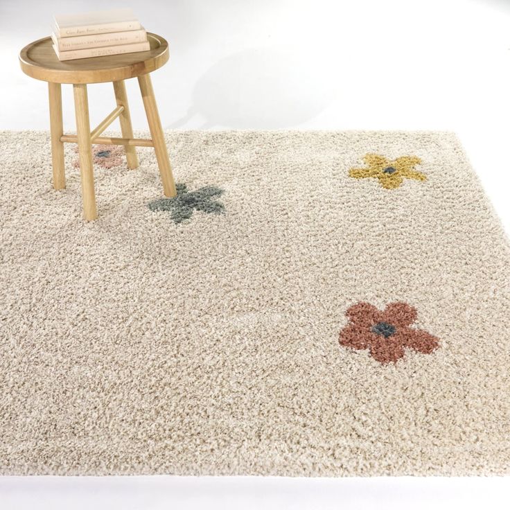 a white rug with flowers on it next to a stool