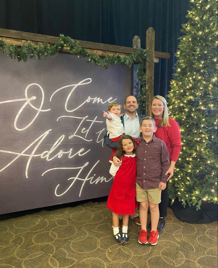 a group of people standing in front of a christmas tree