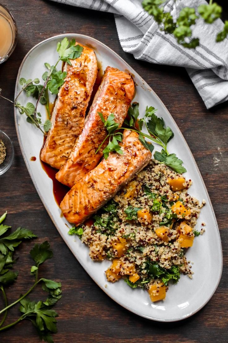 two salmon fillets on a plate with rice and vegetables