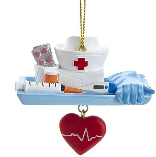 a heart shaped ornament hanging from a hook with medical supplies on it's side