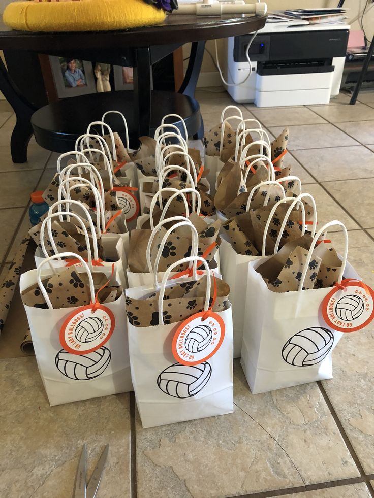 many bags with volleyball designs on them are sitting on the floor next to a table