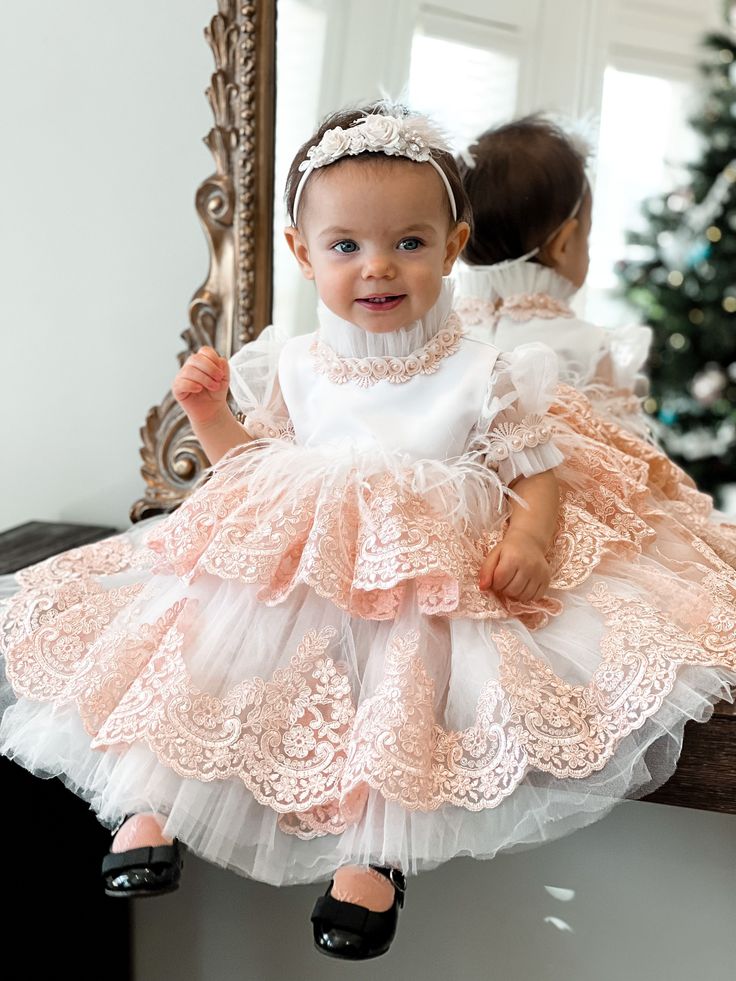 Petite Maison Kids. Gorgeous occasion dress in white color with peachy pink lace embroidery. Feathers on waistline. Faux Mother of Pearl beading. Multiple layers of tulle. Cotton lining on bodice. Back zipper closure. Embroidered Tulle Dress For Ceremonies, Formal Tulle Dress With Feather Trim, Elegant Tulle Dress With Feathers, Pink Long Sleeve Dress With Feather Trim, Fitted Tulle Dress With Feathers, Elegant Embroidered Tulle Gown, White Princess Embroidered Dress, White Princess Style Embroidered Dress, White Embroidered Princess Dress