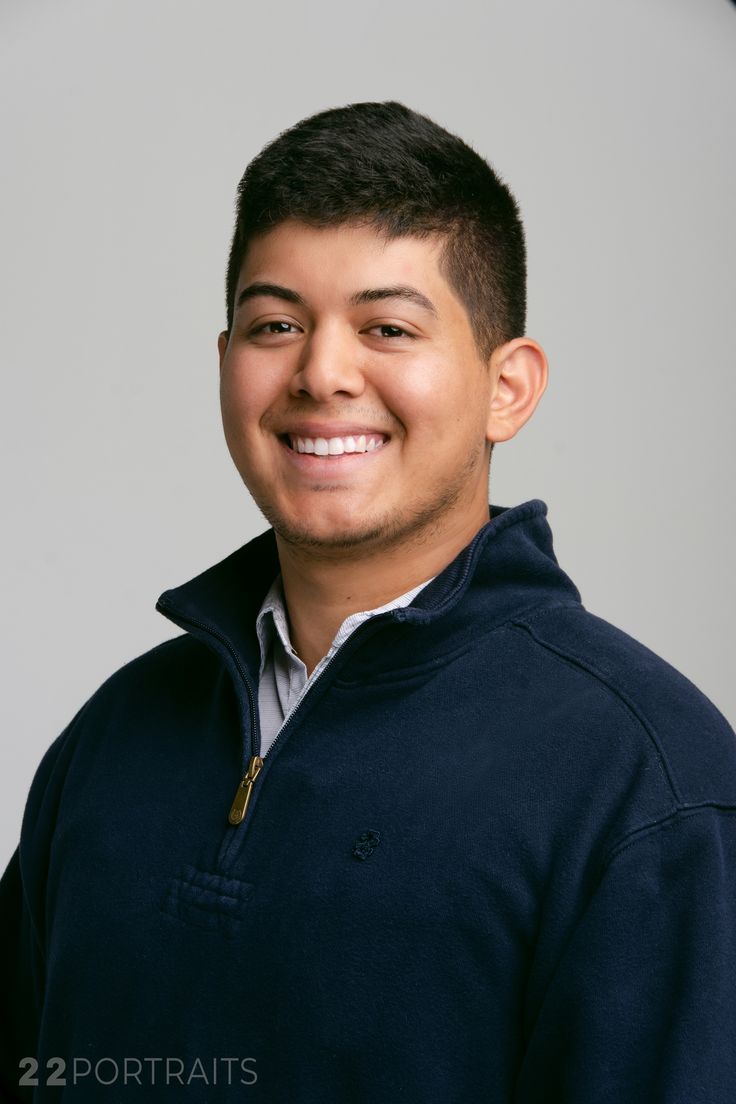 a young man in a blue sweatshirt smiling for the camera with his eyes wide open