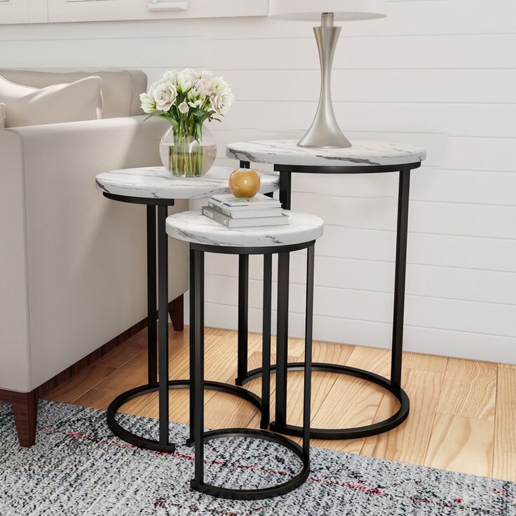 two tables sitting on top of a wooden floor next to a white chair and table