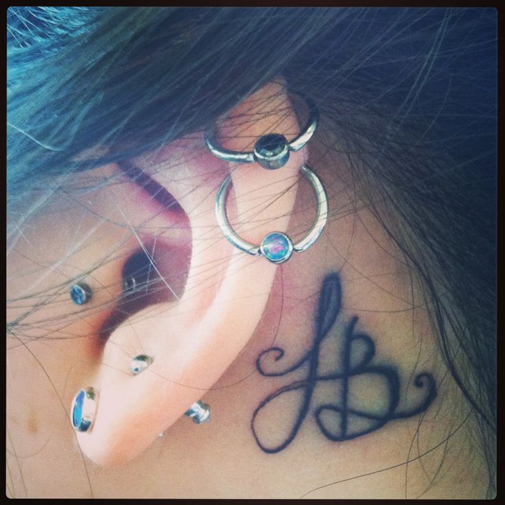 a woman's behind the ear tattoo with letters on her left and right side