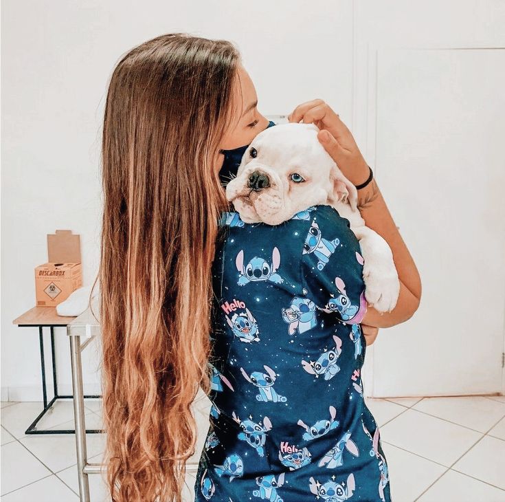 a woman holding a small white dog in her arms and kissing it's face