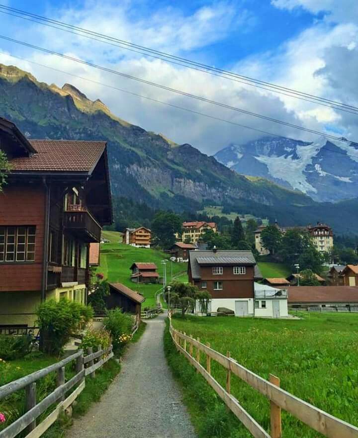 a small village in the mountains with houses on each side and green grass growing all around