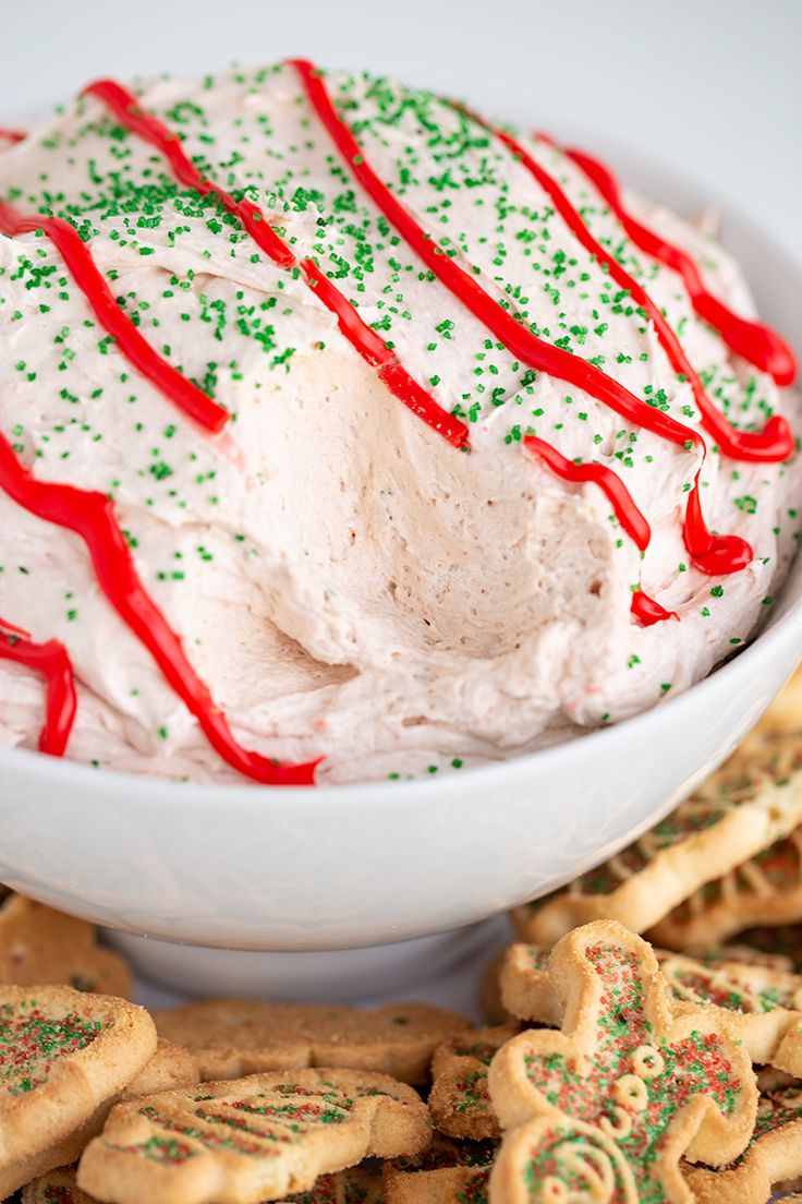 a bowl filled with whipped cream surrounded by cookies and candy canes on a table