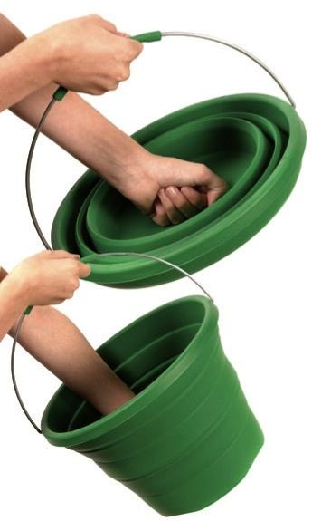 two hands are holding the handles to a green plastic bucket