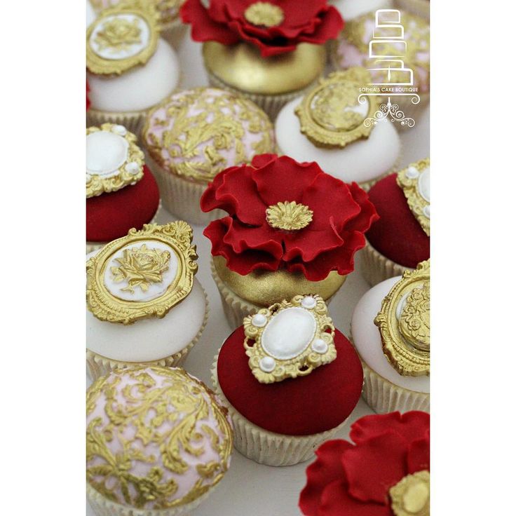 red and gold decorated cupcakes with white frosting on the top, surrounded by golden decorations