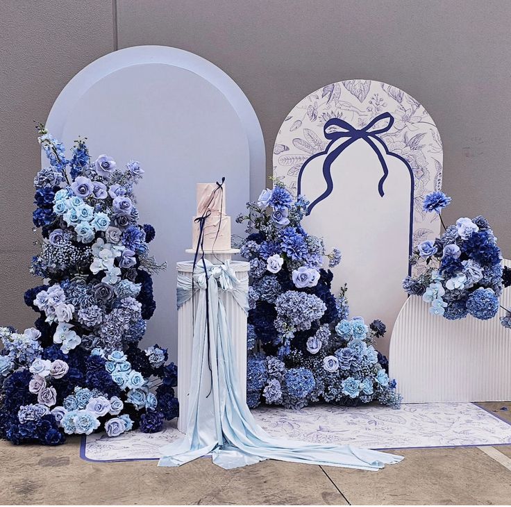 blue flowers are on display in front of an arch with a bow at the top