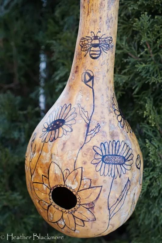 a birdhouse with flowers painted on it's side and a bee in the center