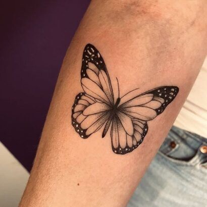 a black and white butterfly tattoo on the arm