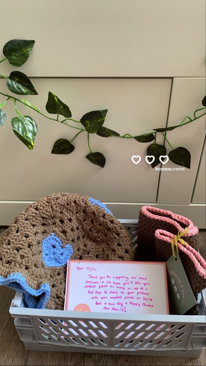 a basket filled with crocheted items next to a plant