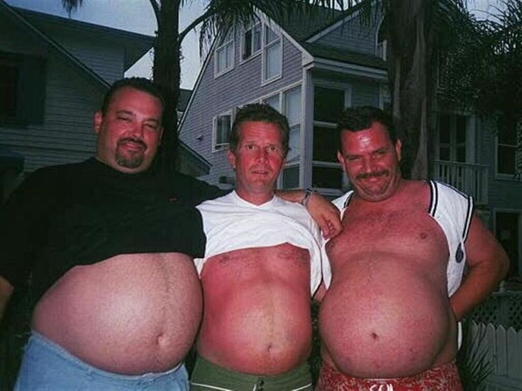 three men standing next to each other in front of a house with large bellys