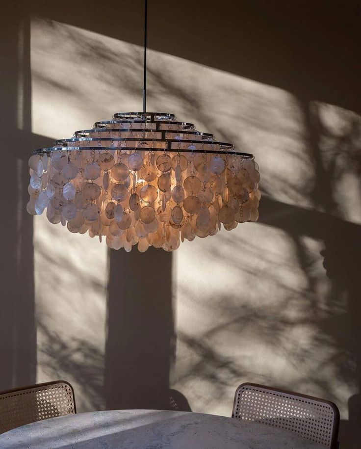 a chandelier hanging over a table in a room with sunlight coming through the window