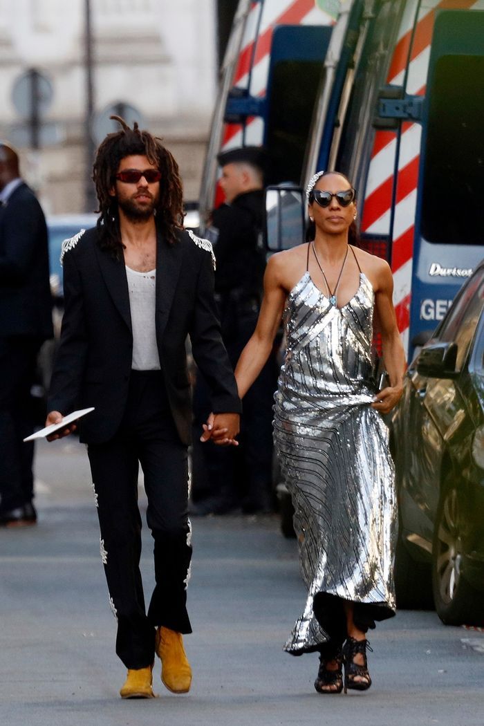 a man and woman are walking down the street holding hands while wearing silver dress clothes