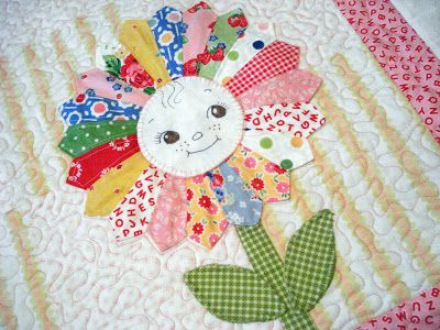 a close up of a quilted table cloth with flowers on it and an appliqued flower in the center