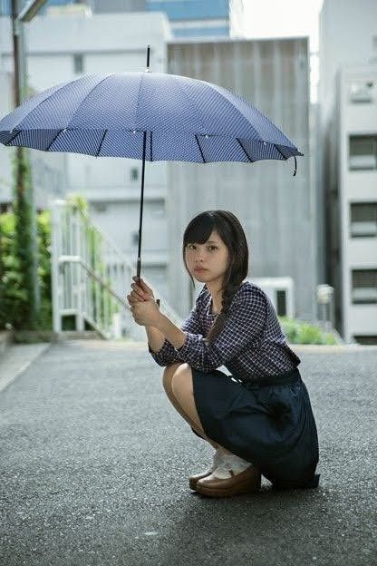 a woman kneeling down while holding an umbrella