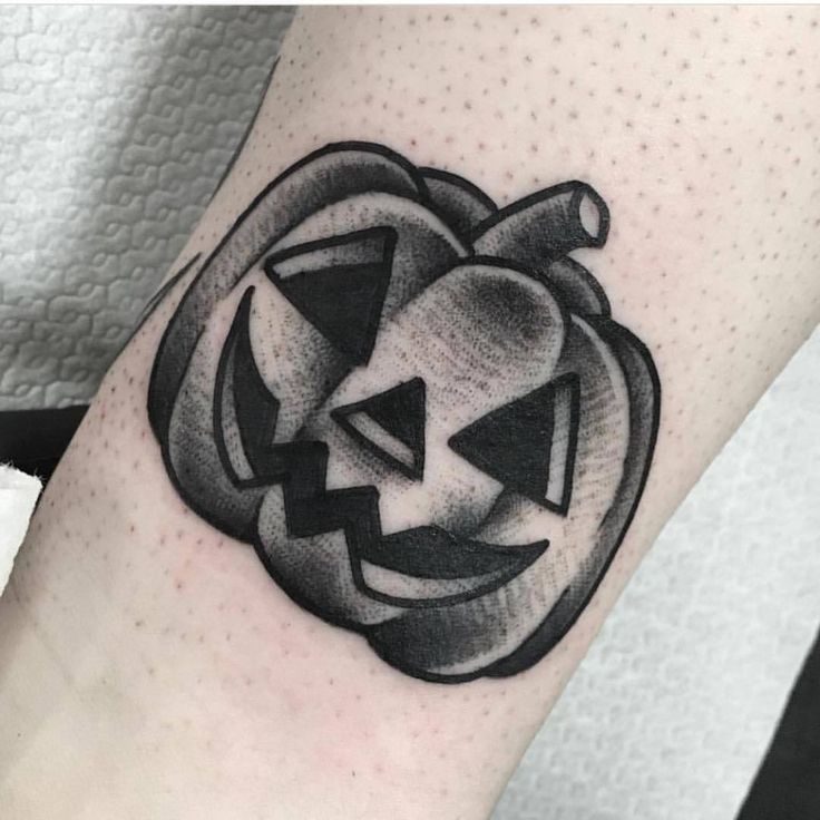 a black and white pumpkin tattoo on the arm