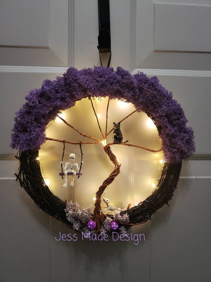 a wreath with purple flowers and lights hanging from it