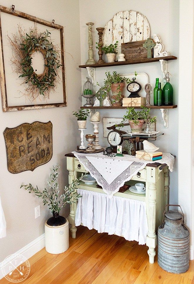 a room with some shelves and plants on the wall next to a table in front of it