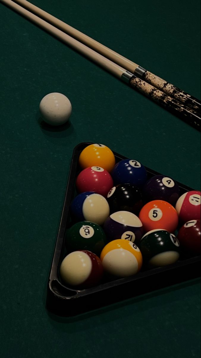 pool balls and cues on a green table