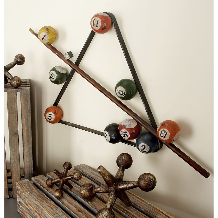 a wooden table topped with pool balls and cues next to a wall mounted rack