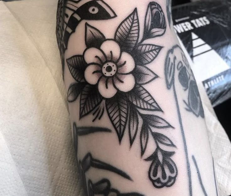 a black and white photo of a flower on someone's left arm, with an arrow in the middle