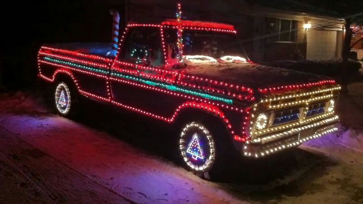 an old red truck with christmas lights on it's bed is parked in the driveway