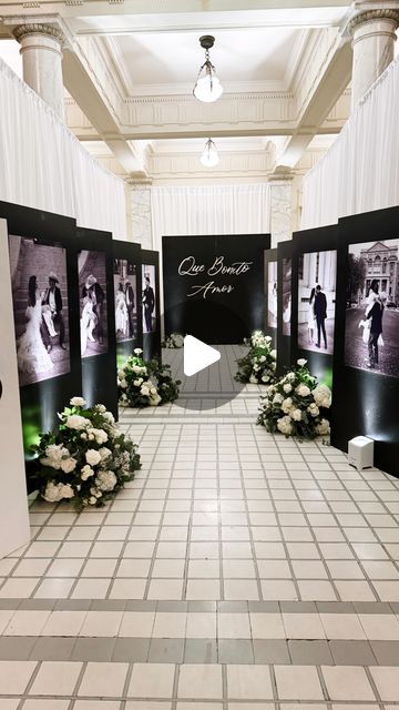 an indoor wedding ceremony with flowers on the floor and pictures hanging from the ceiling in front of them