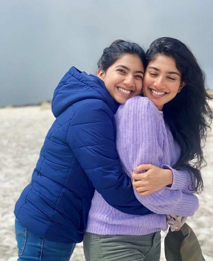 two women hugging each other on the beach