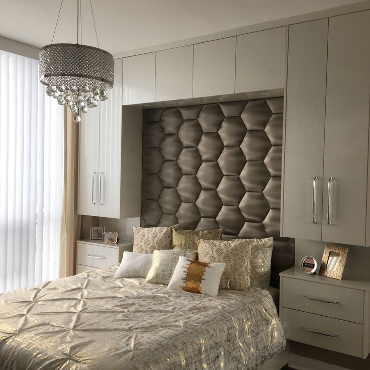 a bedroom with a bed, dresser and chandelier