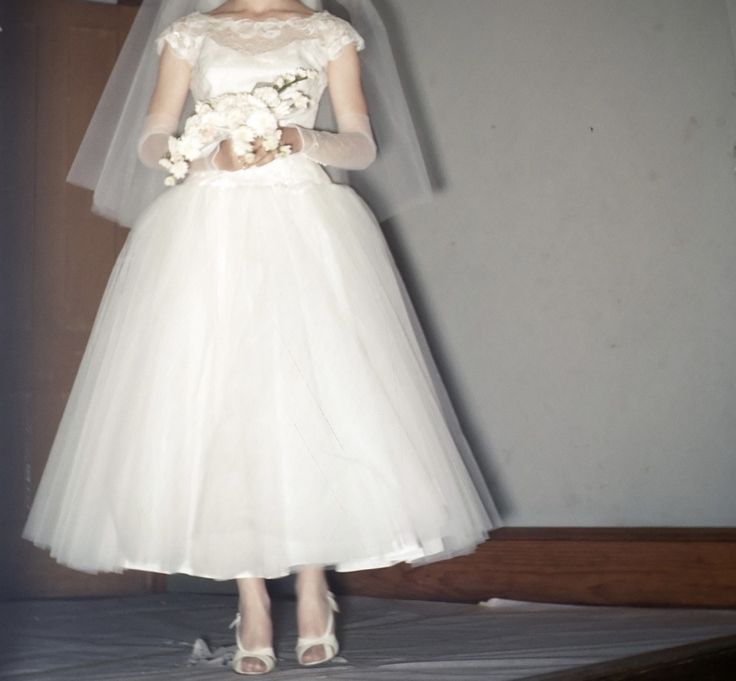 a woman in a wedding dress standing on a bed with her veil over her head