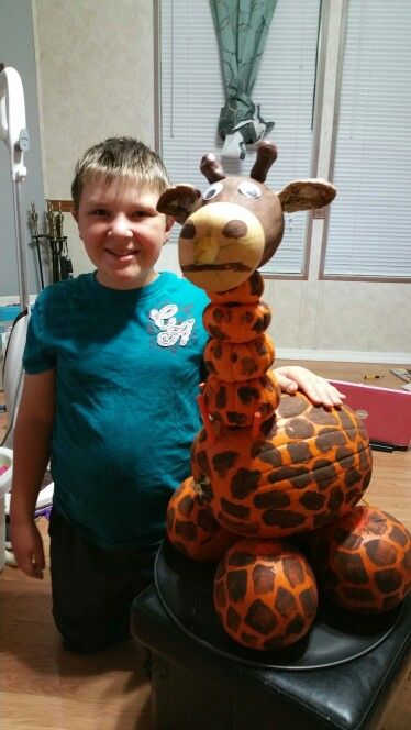 a young boy standing next to a large stuffed giraffe on top of a table