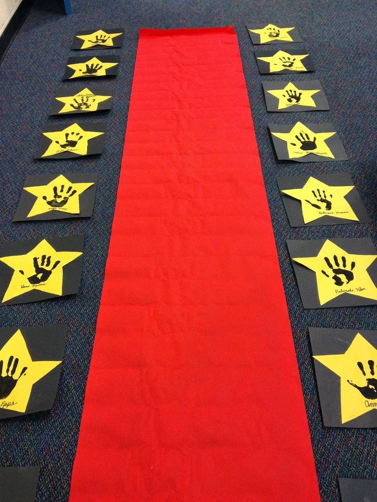 a red carpet with yellow stars and hand prints on it, along with black mats