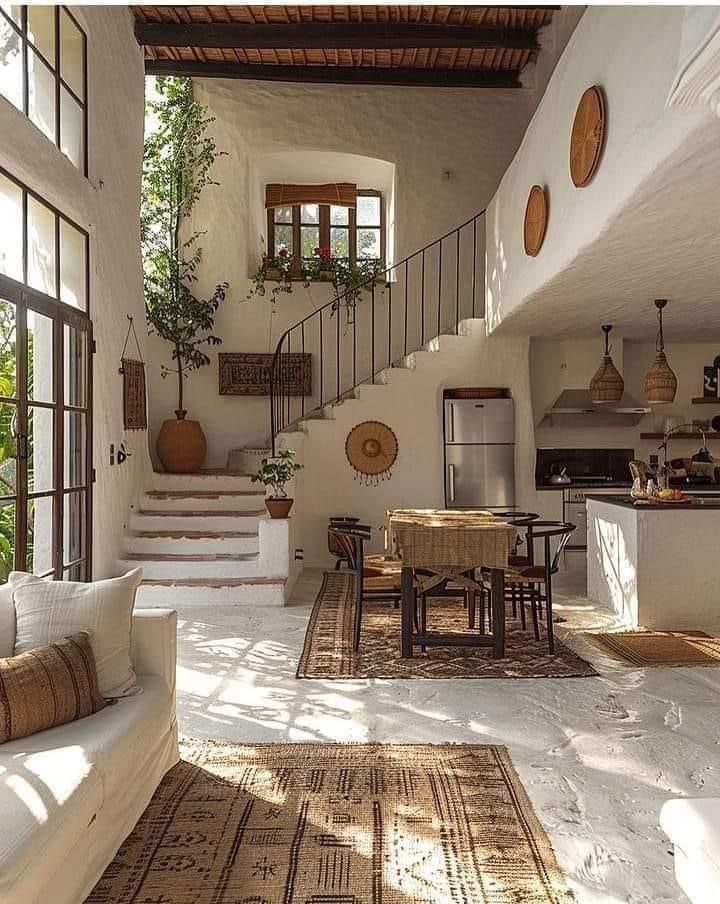 a living room filled with furniture next to a staircase leading up to a kitchen and dining area