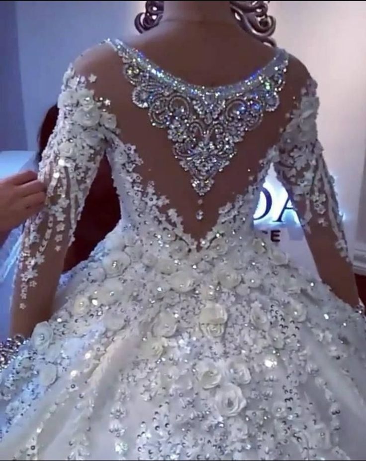 a woman in a white wedding dress is holding onto the back of her dress with sequins on it