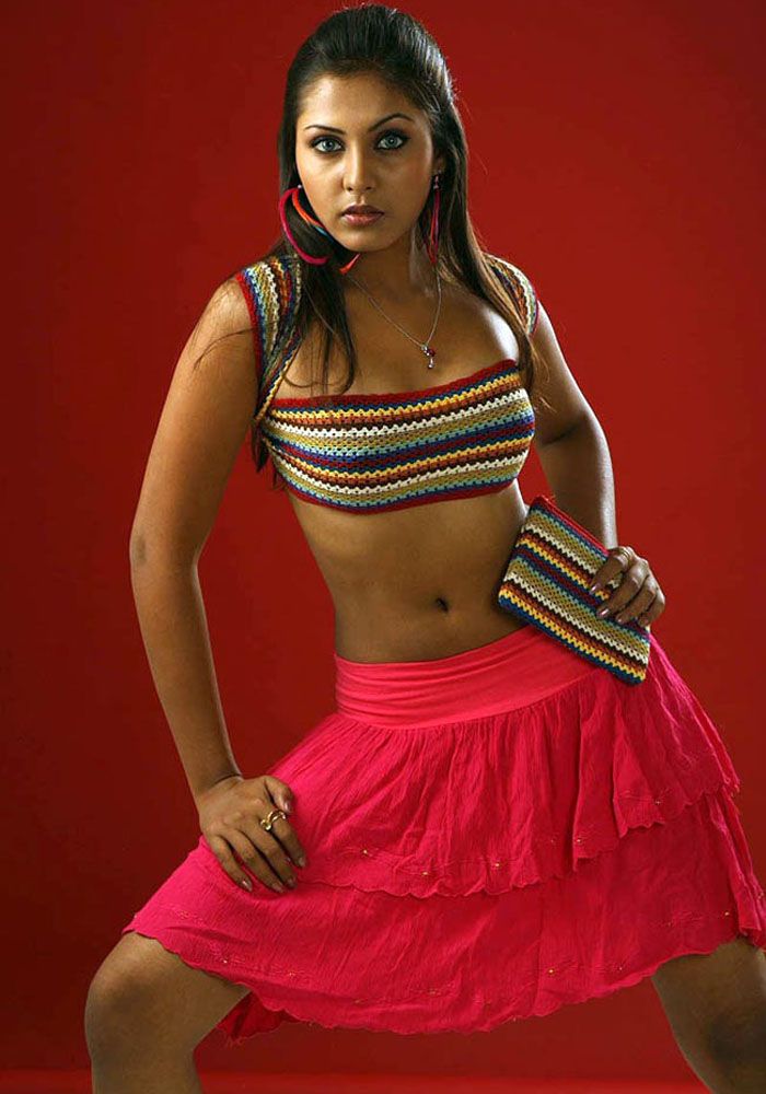 a woman posing in a red skirt and crop top with her hands on her hips