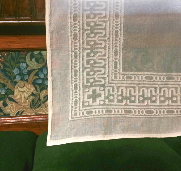 a white towel hanging from the side of a wooden shelf next to a green chair