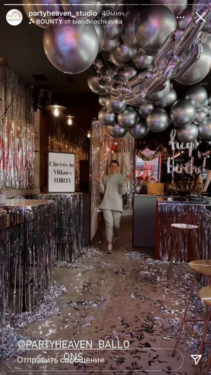 a woman walking through a room filled with balloons and confetti on the ceiling